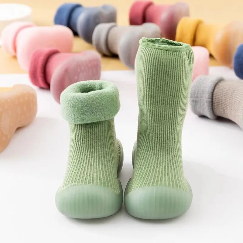 Baby wearing soft first walker sock shoes while learning to walk