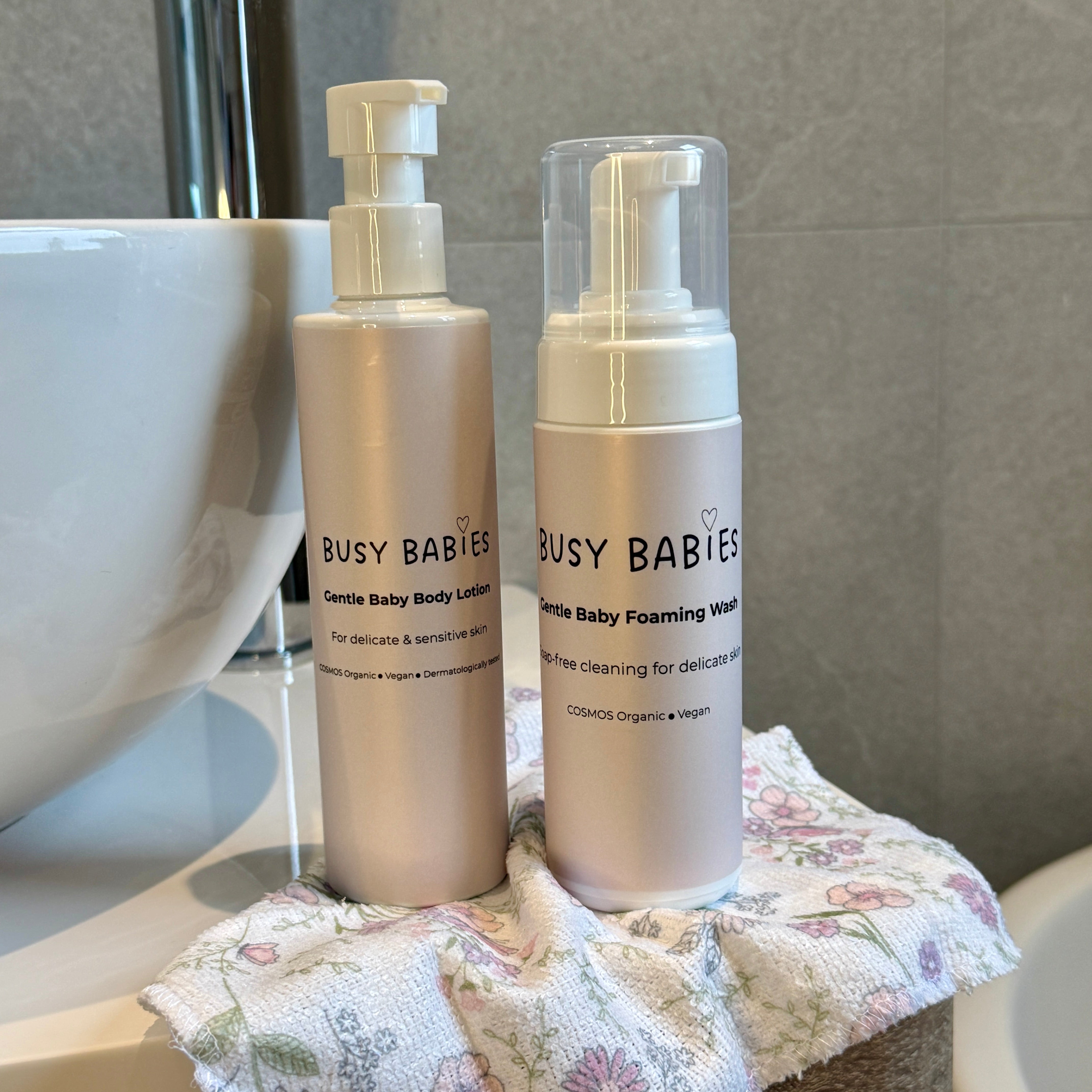 Two bottles of 'Busy Babies' baby care products on a bathroom counter.