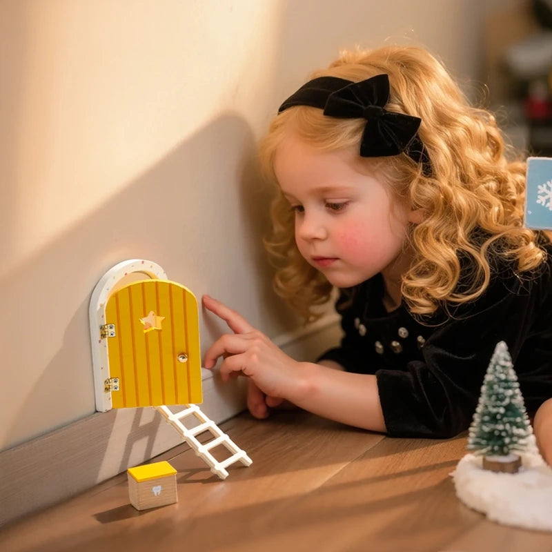 Child playing with a fairy door on a wooden surface