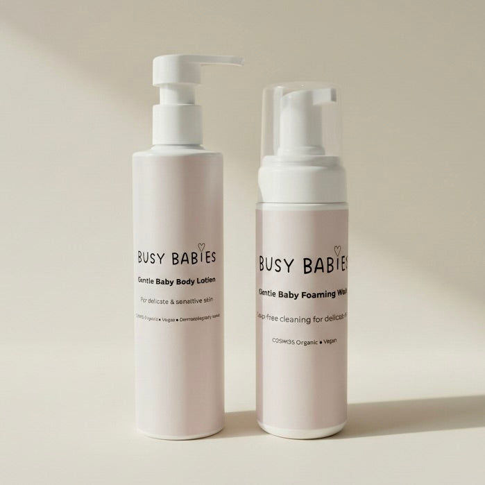 Two bottles of Busy Babies baby care products on a neutral background