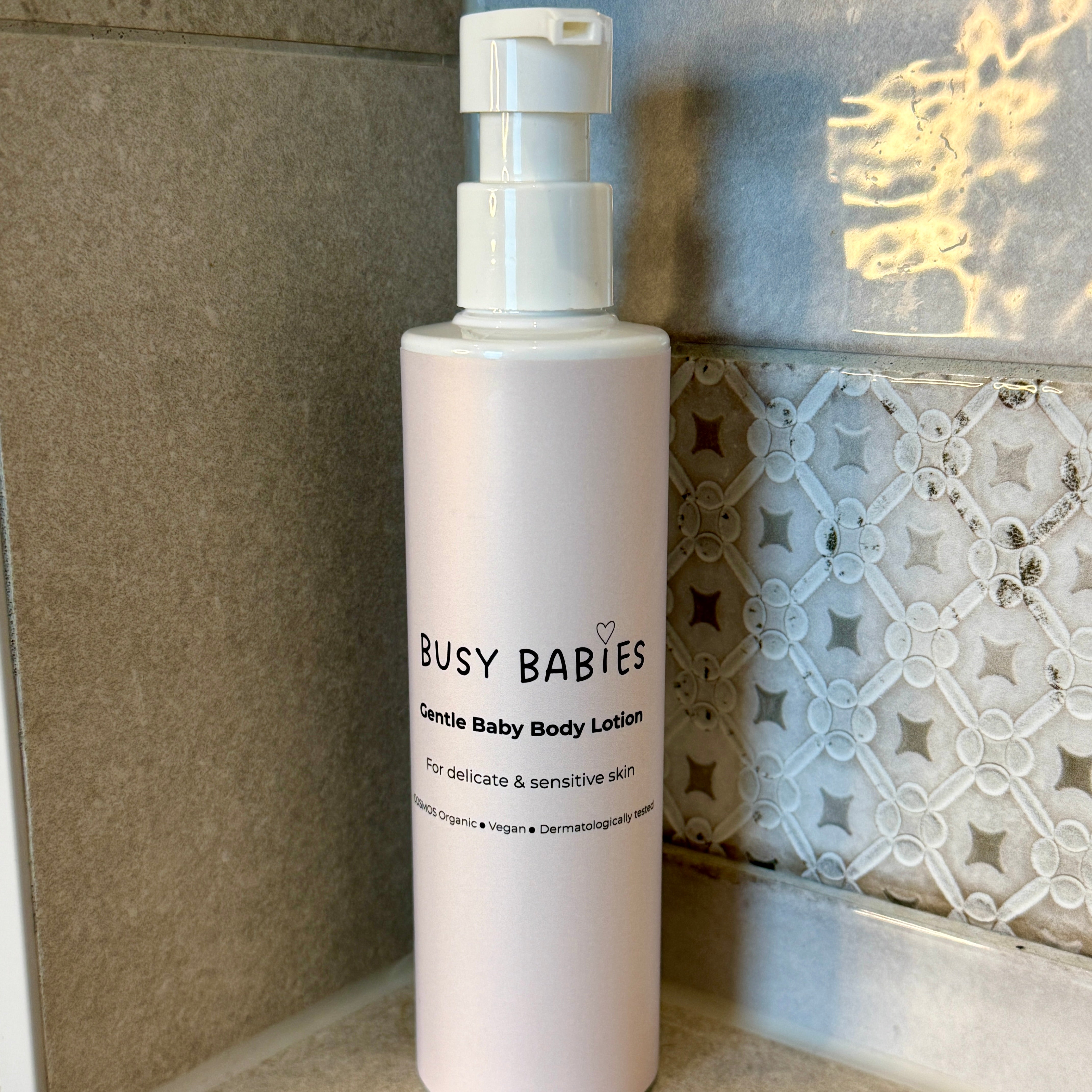 Bottle of Busy Babies Gentle Baby Body Lotion on a bathroom shelf.
