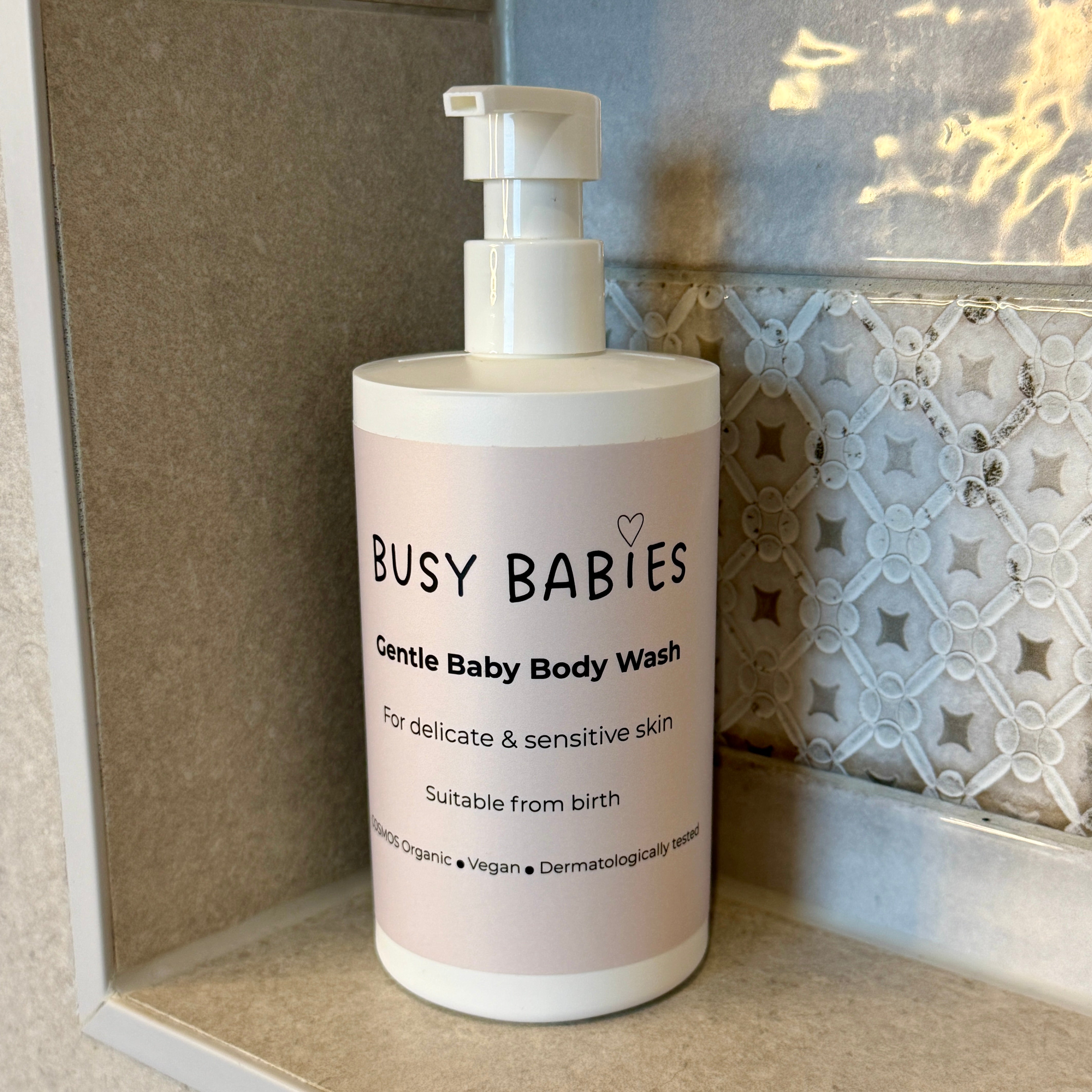 Bottle of 'Busy Babies' Organic Gentle Baby Body Wash on a bathroom shelf.