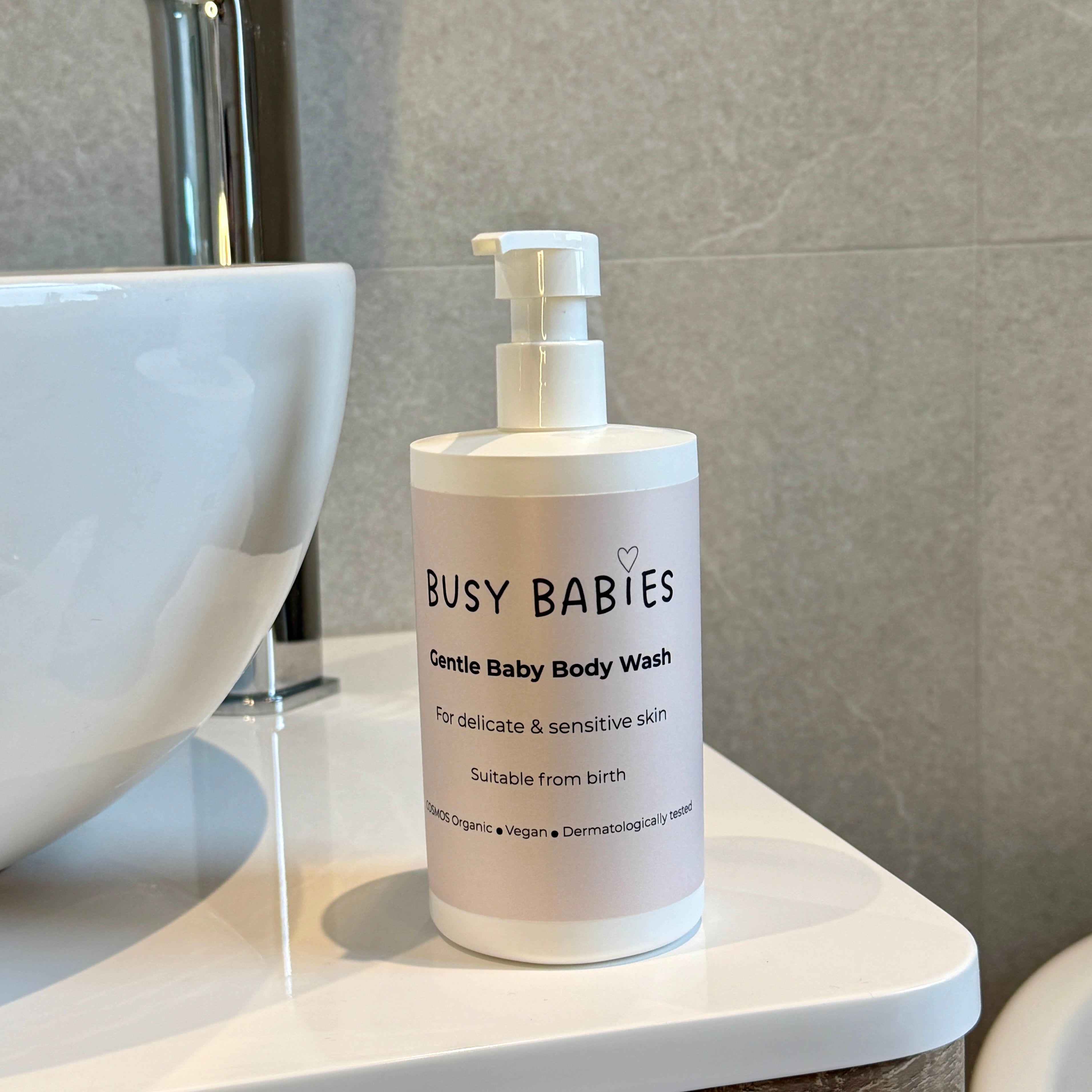 Bottle of Busy Babies COSMOS Organic and Vegan Gentle Baby Body Wash on a bathroom counter.