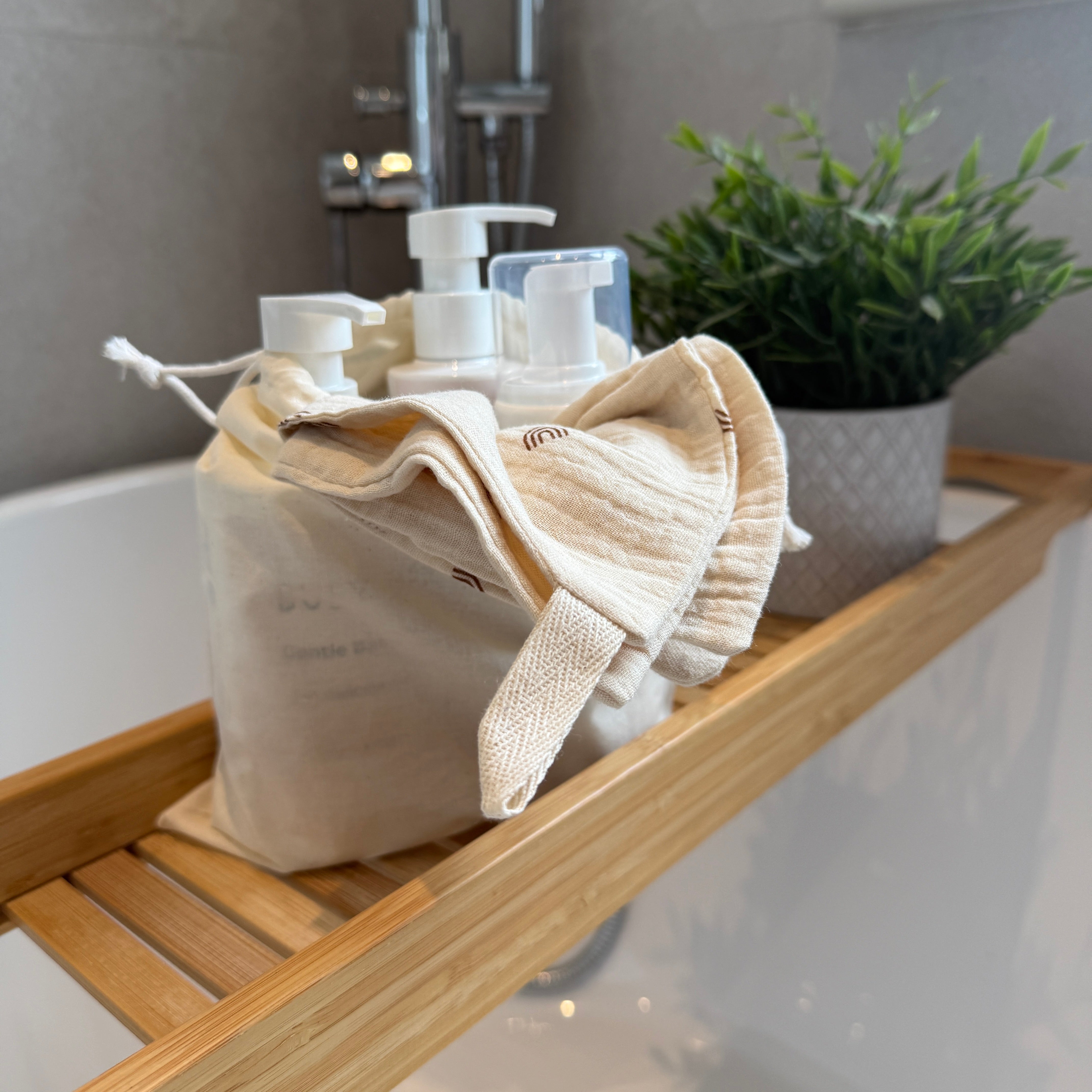 Bathroom shelf with towels, Busy 
Babies bottles, and a plant in a pot.