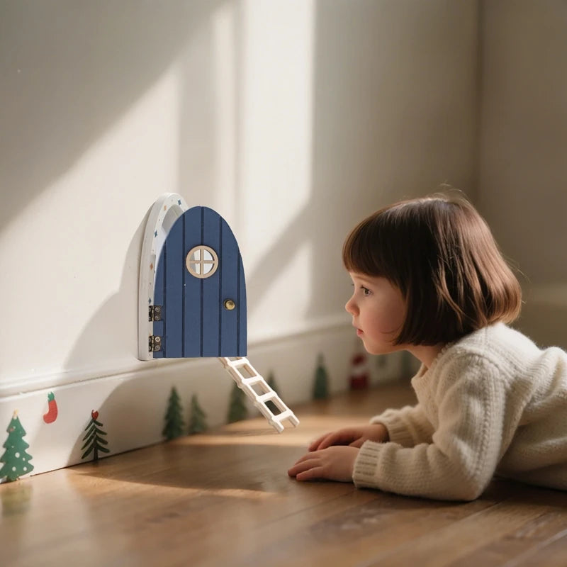 Child looking at a blue fairy door on a wooden floor with Christmas decorations.