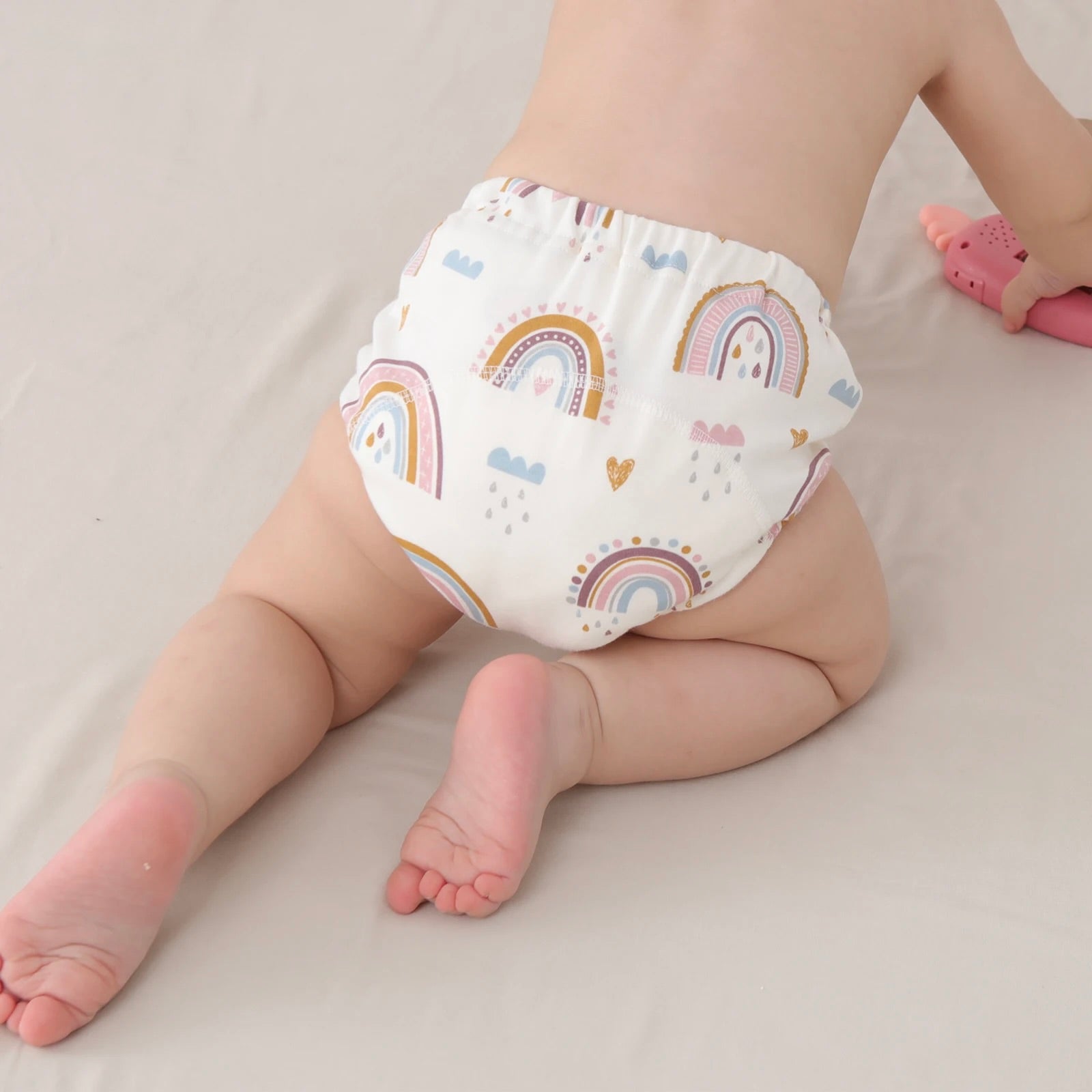 Baby crawling wearing a Baby Cotton Reusable Training Pant with rainbow pattern on a plain background