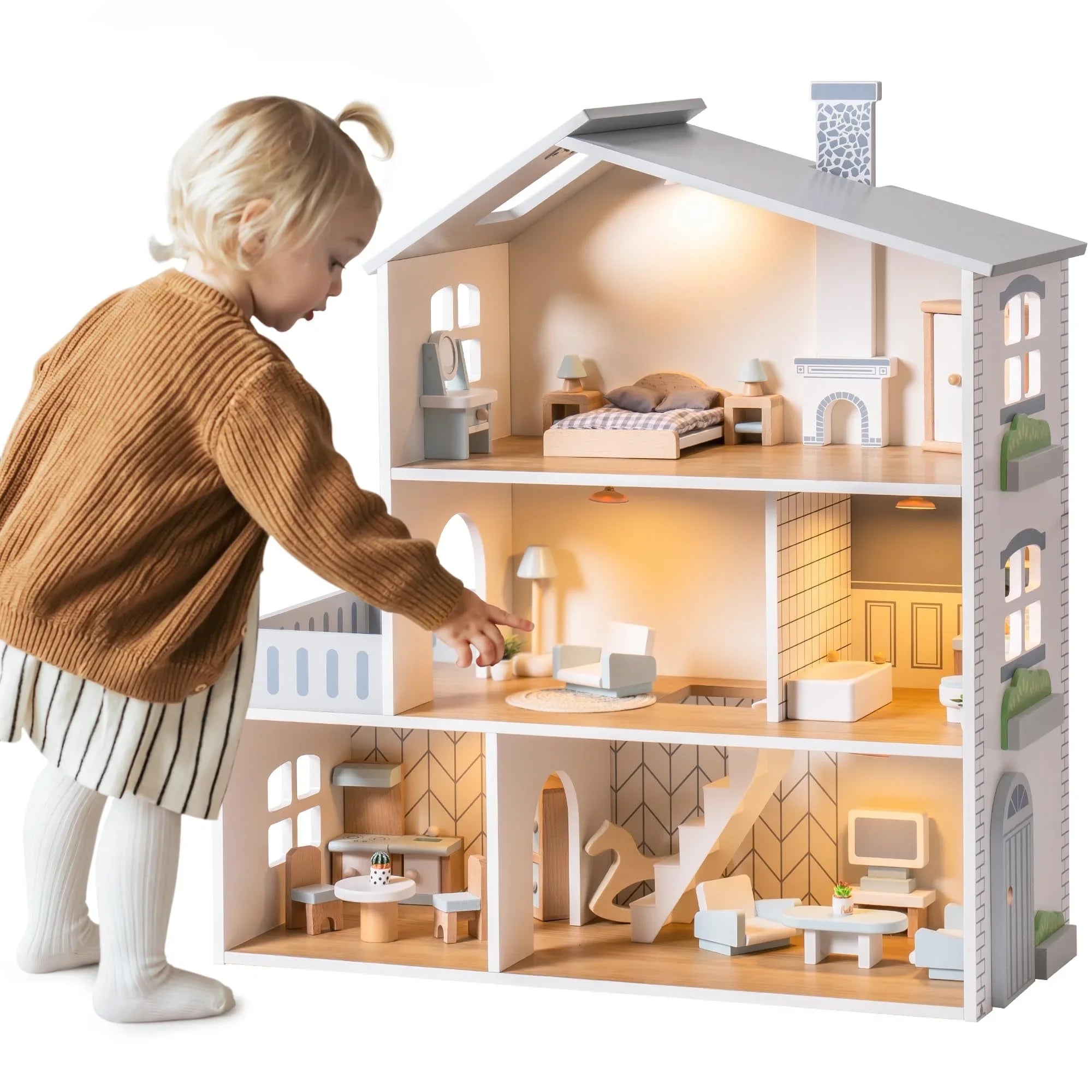 Child playing with a detailed dollhouse on a white background