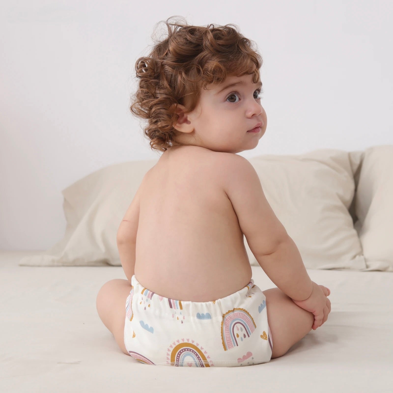 Child wearing Baby Cotton Reusable Training Pants with rainbow pattern on a light background