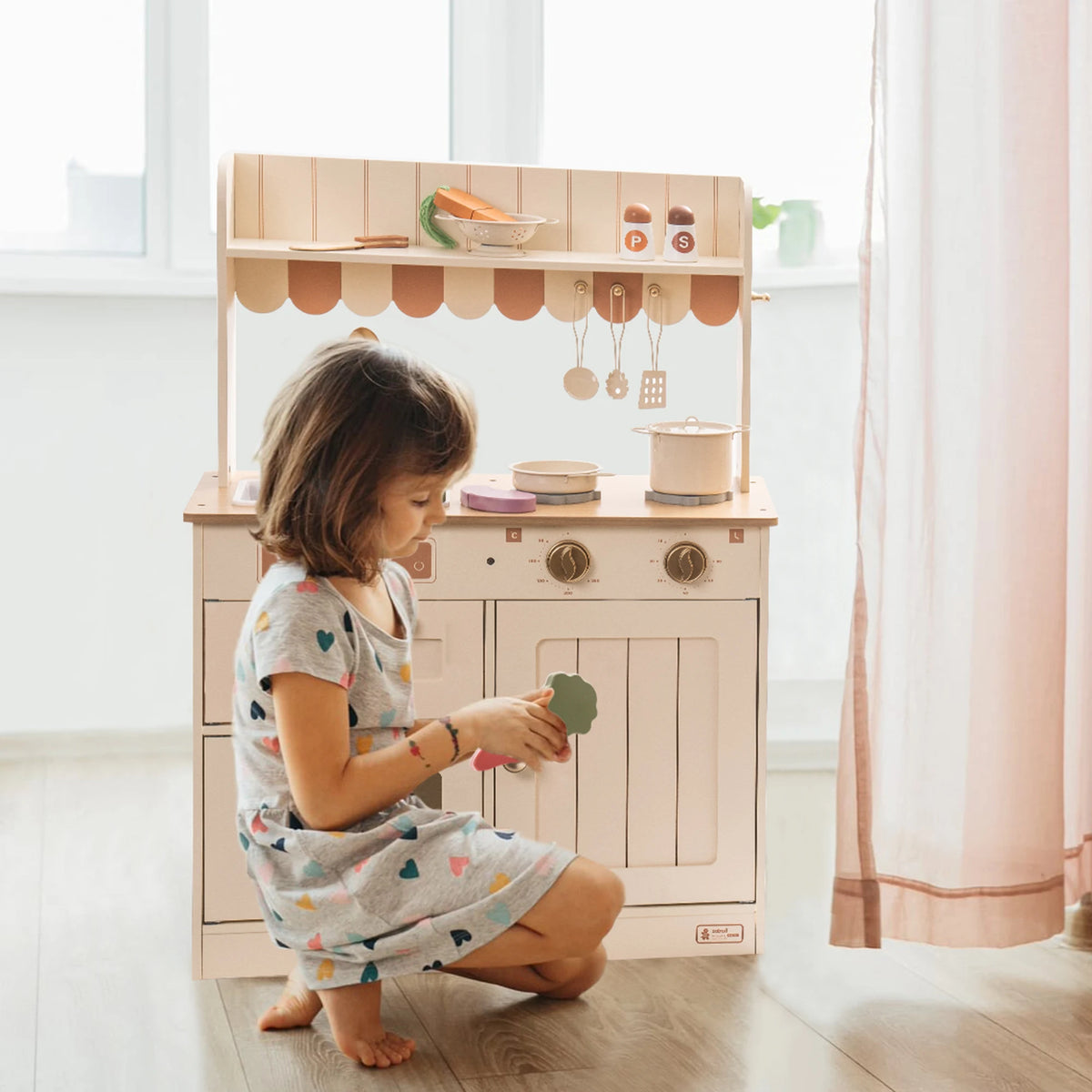 Child playing with a toy kitchen set in a bright room